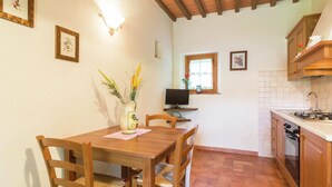 A cozy kitchen with wooden furniture, a dining table, and a TV.