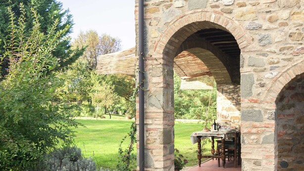 A stone building with an arched doorway leading to a patio area.