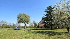 A grassy field with a house, trees, and a blue table. - Holiday Home in Decize Near Beach (Flaine)