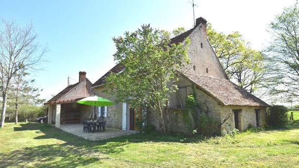 A rustic stone house with a sloped roof, a patio with outdoor furniture, and a green umbrella. - Holiday Home in Decize Near Beach (Flaine)