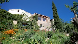 Un edificio histórico con muros cubiertos de hiedra, una torre de piedra y un jardín con diversas flores.