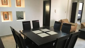 Un salón de conferencias con una mesa de madera oscura, sillas negras y cuadros en la pared.