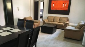 Una sala de estar moderna con comedor, que incluye un juego de sofá, una mesa de centro y una mesa de comedor con sillas.