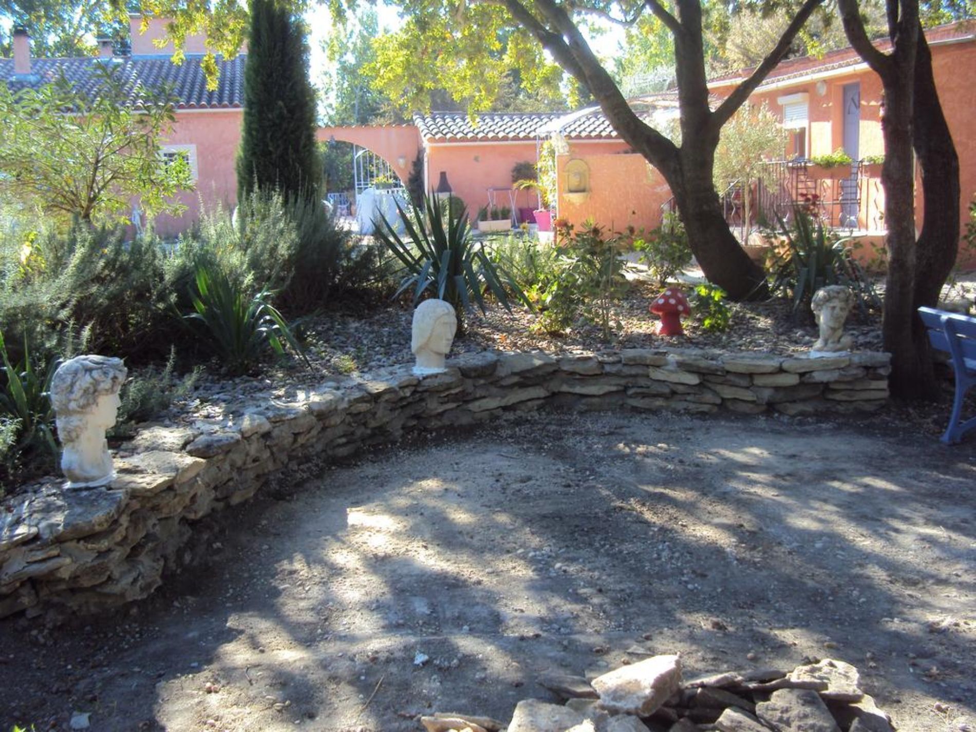A garden with stone walls, statues, and a red fire hydrant.
