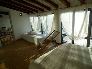 A room with a bed, a wooden chair, a table with chairs, and a window with sheer curtains. - Apartment in Vello by Lake Iseo Beach (Marone)
