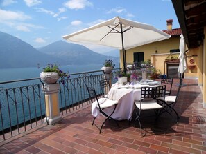 A terrace with a table set for dining, overlooking a body of water and mountains. - Apartment in Vello by Lake Iseo Beach (Marone)