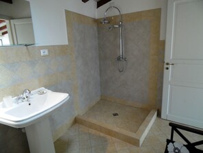 A bathroom with a shower, sink, and tiled walls. - Apartment in Vello by Lake Iseo Beach (Marone)