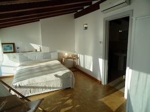 Une chambre à coucher avec un lit, une table de chevet et une vue sur la salle de bain.