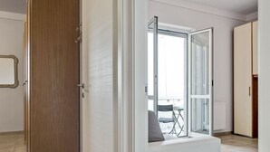 A modern interior with a wooden wardrobe, a glass door leading to a balcony, and a seating area with a view. - Holiday Home in Carrara by the Sea (Carrara)