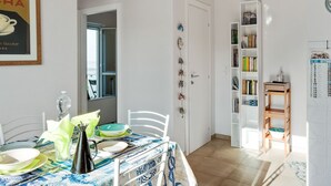 A dining area with a table set for two, a bookshelf, and a door leading to another room. - Holiday Home in Carrara by the Sea (Carrara)