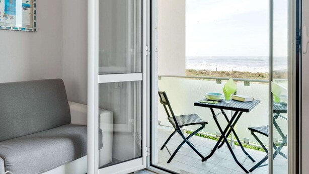 A balcony with a view of the ocean, a gray sofa, and a table with chairs. - Holiday Home in Carrara by the Sea (Carrara)