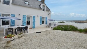 Ein Küstenhaus mit Terrasse, Sitzgelegenheiten im Freien und Meerblick.