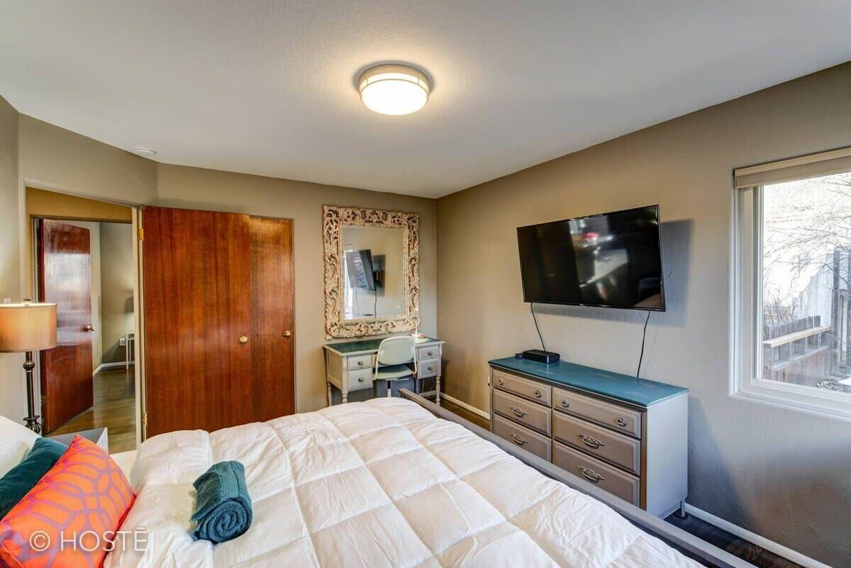 A hotel room with a bed, a desk, a television, and a mirror.
