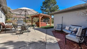 Un patio con mobiliario exterior, un gazebo de madera y una parrilla.