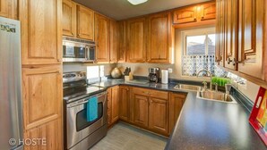 Una cocina con armarios de madera, electrodomésticos de acero inoxidable, un microondas, una estufa y un lavabo.