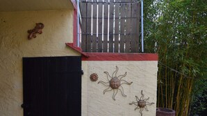 Un edificio con puerta negra, pared roja y beige, y motivos decorativos de sol.