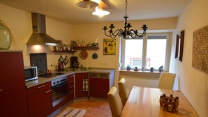 Una cocina con comedor, que incluye estufa, microondas y diferentes utensilios de cocina.