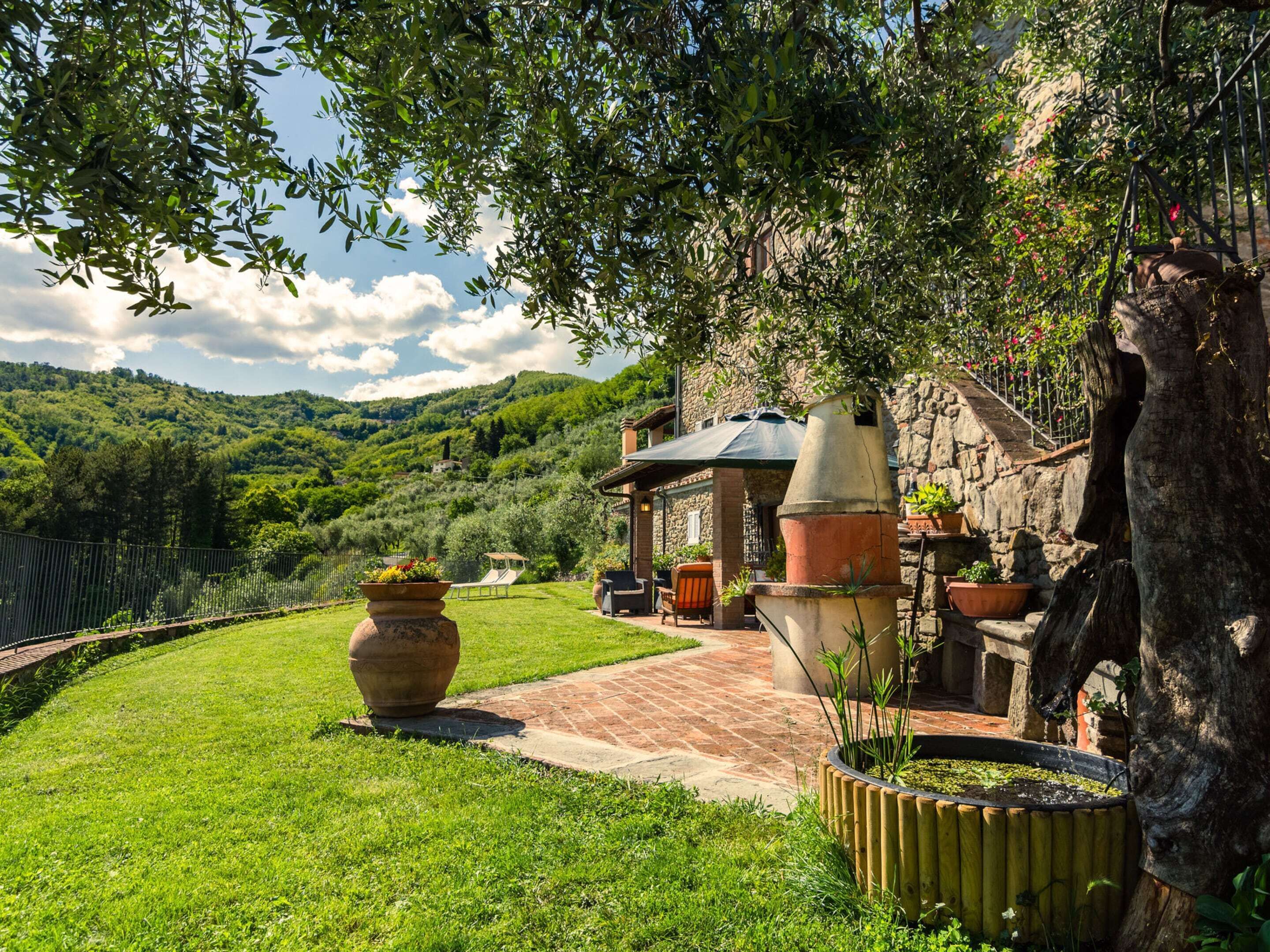 A rustic outdoor area with a stone building, a large planter, and a wooden fence.