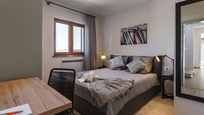 A modern bedroom with a bed, bedside table, chair, and a large mirror.