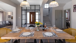A dining area with a wooden table set for four, surrounded by yellow chairs, with a staircase in the background.