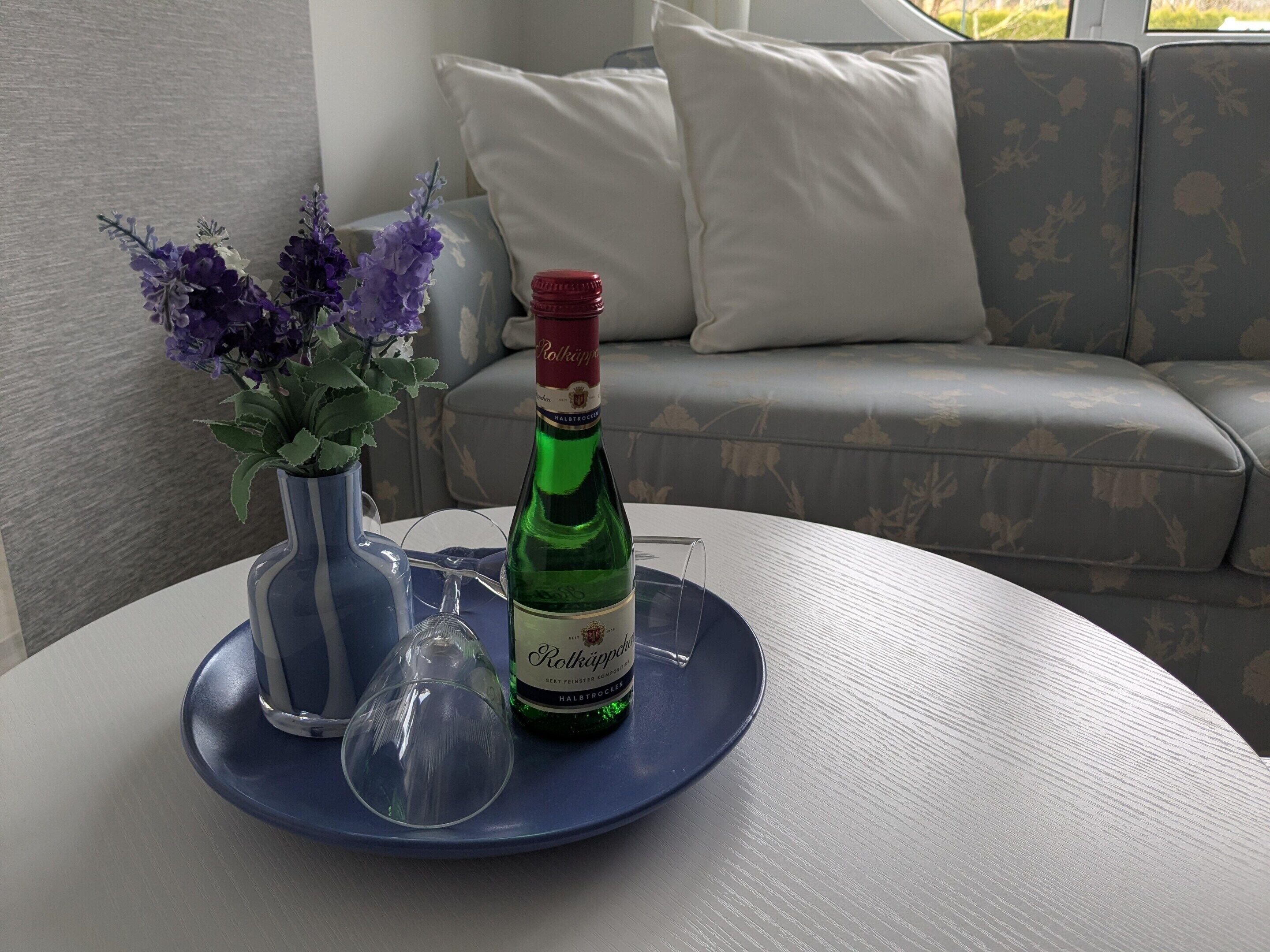 Ein Tisch mit einer Rökäpple-Flasche, einem Glas und einer Vase mit Blumen.