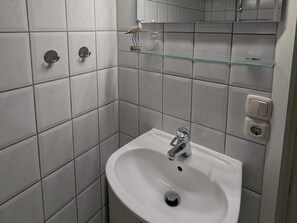 A bathroom with a white sink, a mirror, and a glass shelf. - Charmanter Bungalow in Neubukow Nahe der Ostsee (Neubukow)
