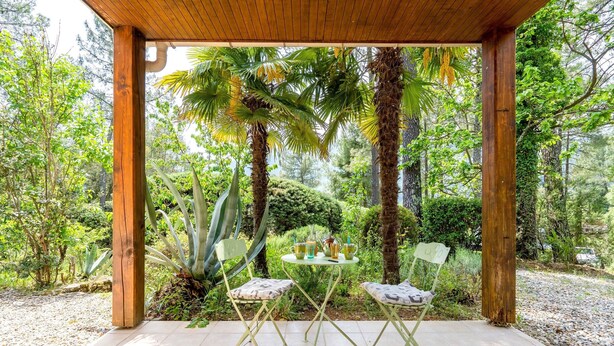 A wooden pergola with a tiled floor, two green folding chairs, and a small table with drinks and a cup. - Family Escape in Les Salelles (Les Salelles)