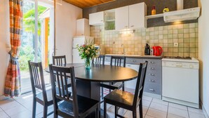 A kitchen with a dining table, chairs, a refrigerator, a stove, and a tiled backsplash. - Family Escape in Les Salelles (Les Salelles)