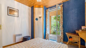 A bedroom with a bed, a chair, a desk, and a door leading to a balcony. - Family Escape in Les Salelles (Les Salelles)