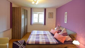 A bedroom with a bed, a nightstand, a lamp, a window, and a door. - Apartment in the Pfaffenwinkel District (Prem)