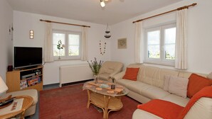 A living room with a sofa, a coffee table, a TV, and a window with curtains. - Apartment in the Pfaffenwinkel District (Prem)