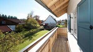 A wooden balcony with a view of a green lawn and neighboring houses. - Apartment in the Pfaffenwinkel District (Prem)