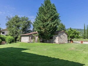 Surrounded by lush greenery, this serene stone house offers a peaceful retreat amidst a beautiful landscape.