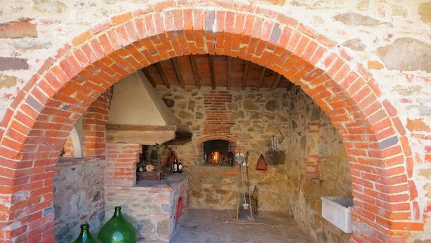 An arched brick oven with a stone interior, a stone floor, and two green glass bottles on the left. - Spacious Holiday Home (Bucine)