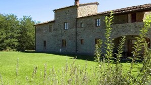 A stone building with a tiled roof, a grassy courtyard, and a small arched entrance. - Spacious Holiday Home (Bucine)