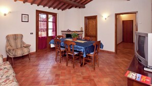 A dining area with a wooden table and chairs, a fireplace, and a television on a wooden table. - Spacious Holiday Home (Bucine)
