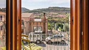 Un balcone con vista su un'area di parcheggio, edifici e un paesaggio collinare.