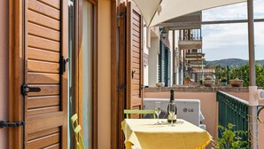 Un balcone con un tavolo apparecchiato per due persone, una bottiglia di vino e una sedia.