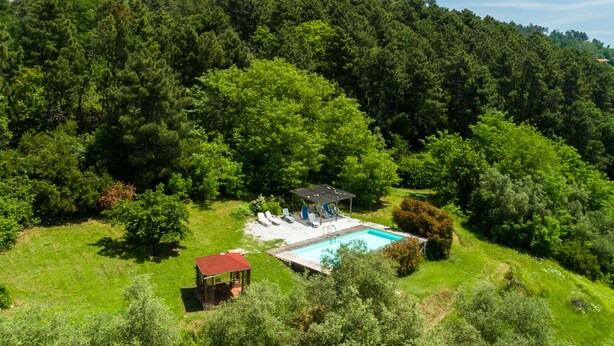 A pool area with a gazebo, lounge chairs, and a small deck.