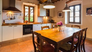 A kitchen with wooden beams, white cabinets, and a dining table with chairs.