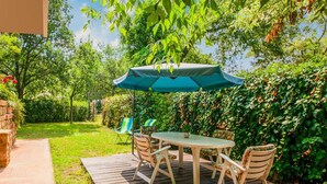 A wooden deck with a table and chairs, surrounded by greenery and a brick wall. - Splendid Holiday Home in Altopascio With Garden (Altopascio)