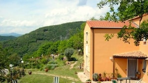 A house with a red-tiled roof, a small patio with outdoor furniture, and a well-maintained garden. - Woodland Escape With Pool (Vezzi Portio)