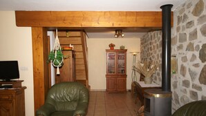 A living room with a fireplace, a wooden cabinet, a green leather chair, and a television. - Cozy Family Home in Saint-pons (Saint-Pons)