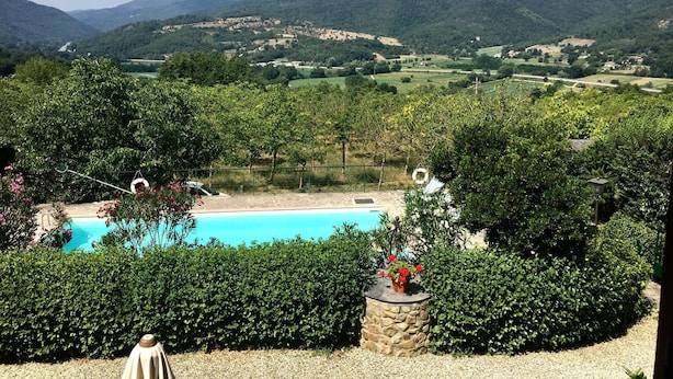Una piscina envoltada de vegetació abundant i turons al fons.