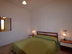 A bedroom with a single bed, two bedside tables, a nightstand, a mirror, and two wall-mounted lamps. - Residence With Pool, Near the Beach and Coastal Town of La Ciacca (Valledoria)