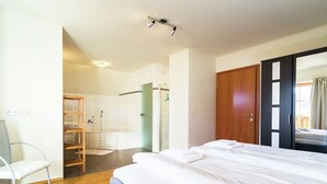 A hotel room with a bed, a wooden floor, a bathroom with a shower, and a wardrobe. - Chalet in ski Area in Mauterndorf With Sauna (Mauterndorf)