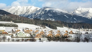 A winter resort with wooden cabins and a view of snow-covered mountains. - Chalet in ski Area in Mauterndorf With Sauna (Mauterndorf)