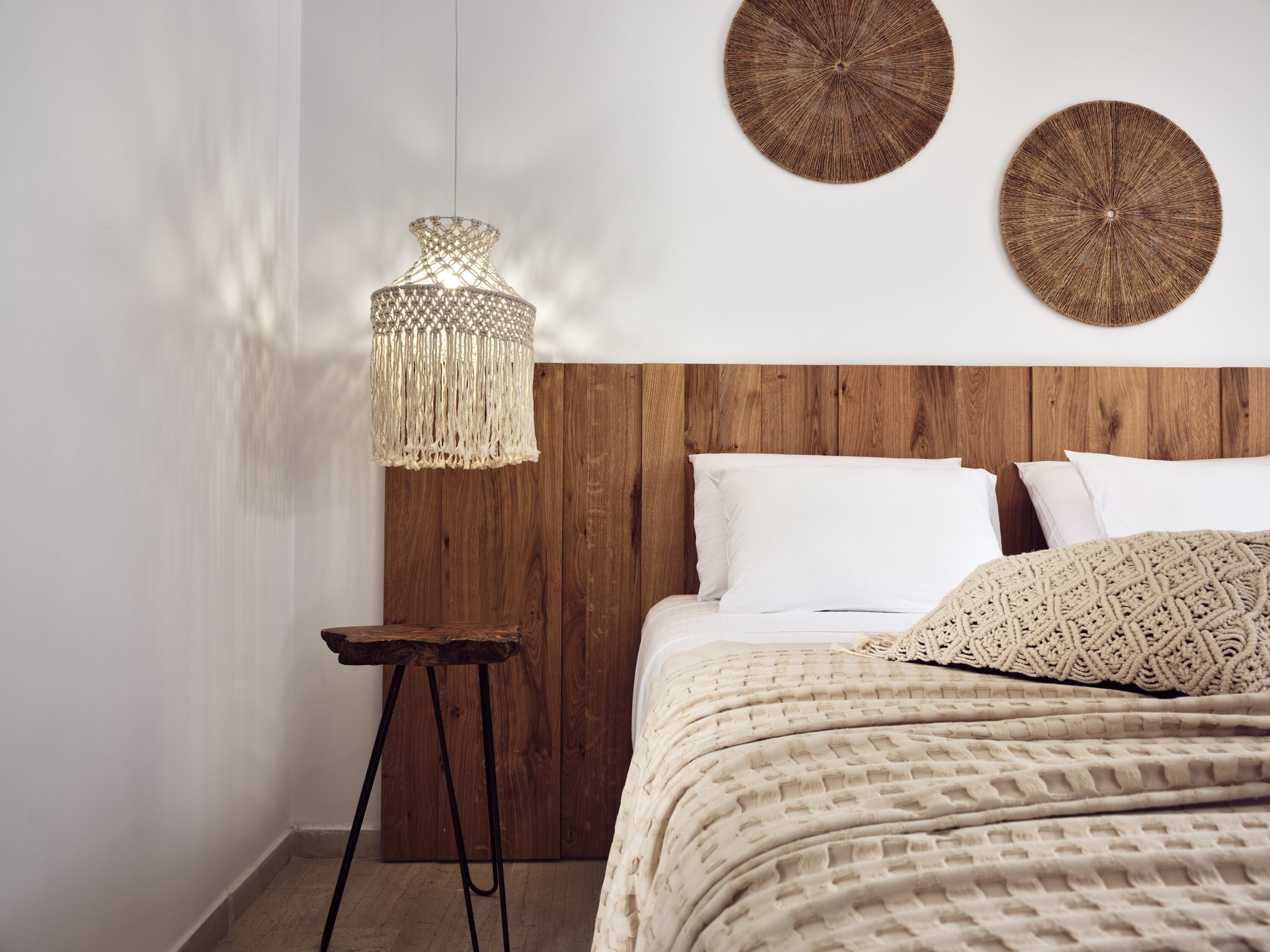 A bedroom with a wooden headboard, a hanging light fixture, and two wall-mounted round decorations.