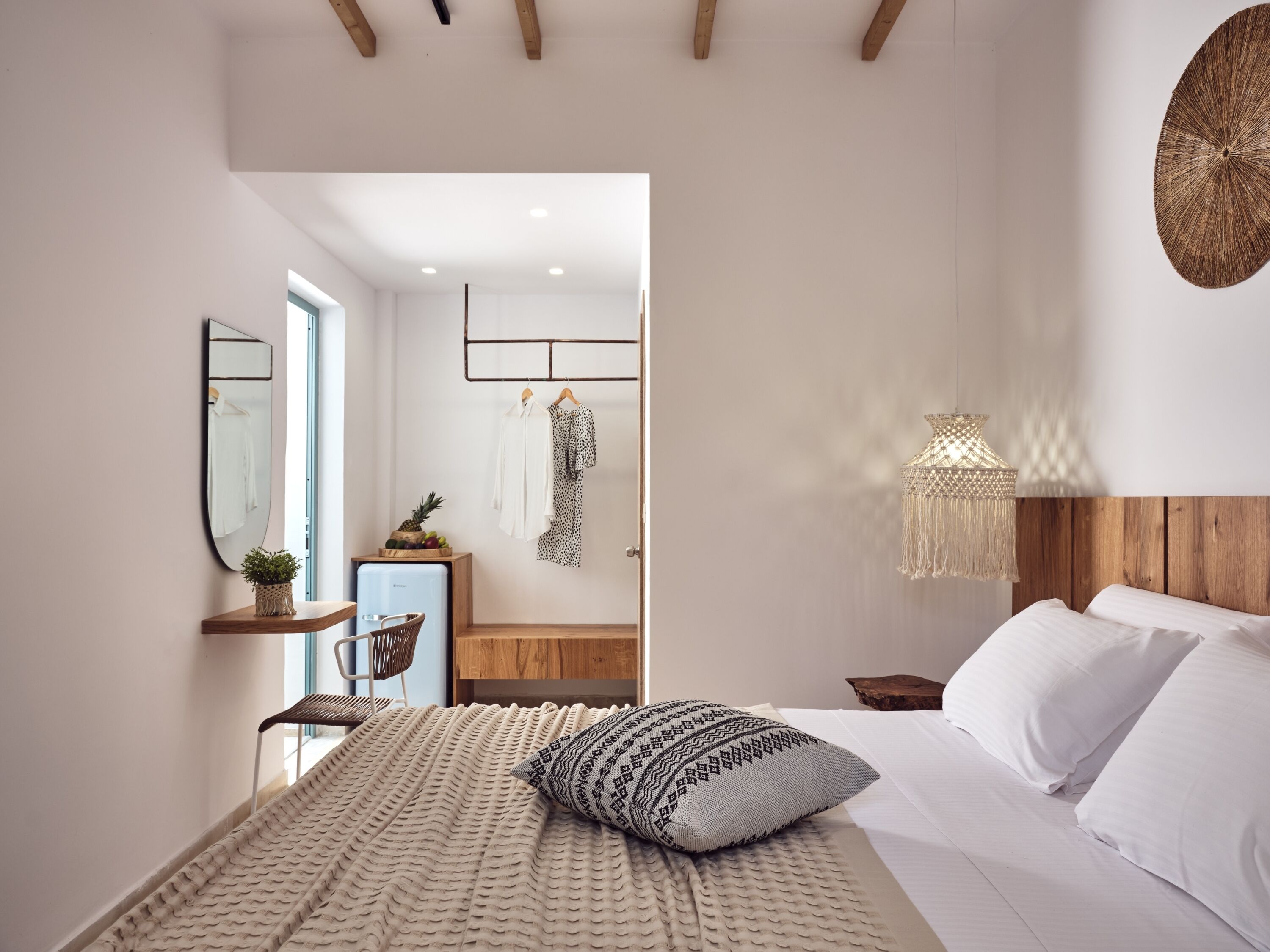 Ein Schlafzimmer mit einem Bett, einem Nachttisch, einer Hängeleuchte und einem Spiegel an der Wand.
