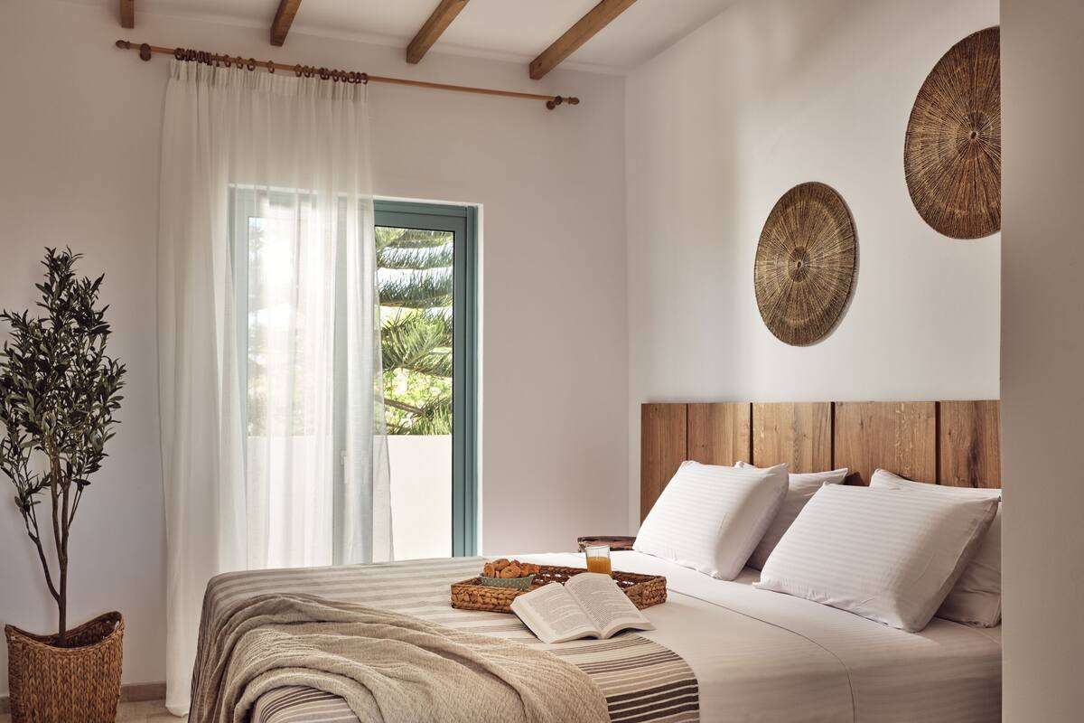 Une chambre à coucher avec un lit, une fenêtre avec des rideaux, une plante et deux éléments de décoration murale.
